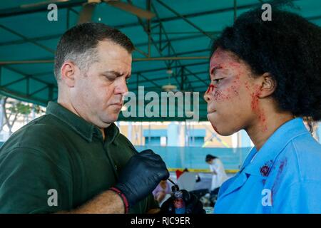 Rohm Kern eine Make-up-Artist von Südflorida, schafft simulierten verletzt zu einem Freiwilligen in eine gemeinsame Übung auf dem Homestead-Miami Speedway in Miami, Fla., Jan. 11, 2018. Diese jte konzentrierte sich auf den Aufbau von Kapazitäten und der nahtlose Übergang zwischen den örtlichen Ersthelfern und die Unterstützung durch die Nationalgarde und aktiven Soldaten zur Verfügung gestellt. (U. S. Armee Stockfoto