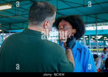 Rohm Kern eine Make-up-Artist von Südflorida, schafft simulierten verletzt zu einem Freiwilligen in eine gemeinsame Übung auf dem Homestead-Miami Speedway in Miami, Fla., Jan. 11, 2018. Diese jte konzentrierte sich auf den Aufbau von Kapazitäten und der nahtlose Übergang zwischen den örtlichen Ersthelfern und die Unterstützung durch die Nationalgarde und aktiven Soldaten zur Verfügung gestellt. (U. S. Armee Stockfoto