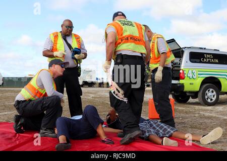 Mitglieder des Miami-Dade Feuerwehr Feuerwehr- und Rettungskräfte, reagieren auf die simulierten Verletzungen eines Freiwilligen bei einer gemeinsamen Übung von der Dade Feuerwehr und Homestead-Miami Speedway in Miami, Fla., Jan. 11, 2018 gehostet wird. Diese jte konzentrierte sich auf den Aufbau von Kapazitäten und der nahtlose Übergang zwischen den örtlichen Ersthelfern und die Unterstützung durch die Nationalgarde und aktiven Soldaten zur Verfügung gestellt. (U. S. Armee Stockfoto