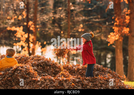 Junge und Mädchen spielen in einem Stapel von Blättern, United States Stockfoto