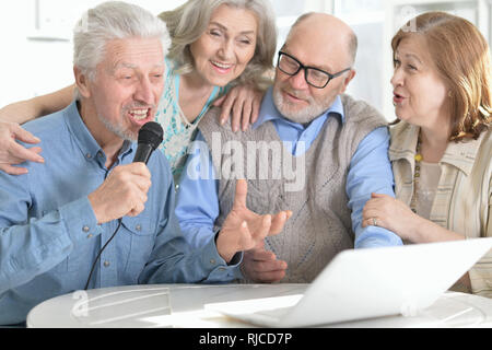 Porträt von zwei ältere Ehepaare an Tisch und Karaoke singen Sitzen Stockfoto