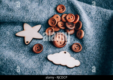 Holz- Schaltflächen, die zufällig auf einem grauen Hintergrund platziert sind. Weiter Holzspielzeug silhouette Lamm, Stern, Monat, Berg, Kaktus, Weihnachtsbaum auf einem grauen Stockfoto