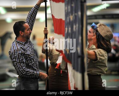 Freiwillige bis eine Flagge als Hintergrund für Fotos verwendet, während ein homecoming Event durch Ehre Flug von West Central Florida am internationalen Flughafen St. Pete-Clearwater Nov. 1, 2016 gehostet. Nach jeder Veteran machten sich auf den Weg durch die Menge der Menschen, die sie hatten die Wahl ein Foto mit ihren Vormund zu nehmen. Stockfoto