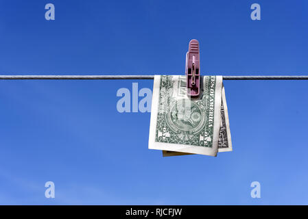 Geldwäsche von einem US-Dollar bill Hinweis aus den USA auf eine Wäscheleine mit blauem Himmel für AML Anti Geldwäsche Finance Geschäft Kriminalität Ideen Stockfoto