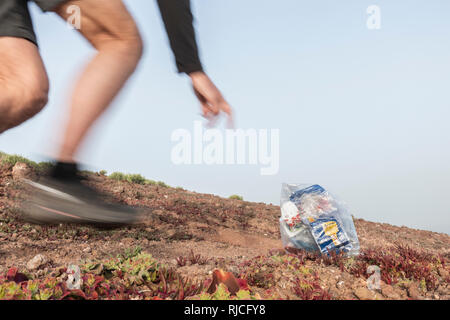 Plogging: Ein Jogger Abholung Wurf beim Joggen (plogging). Stockfoto