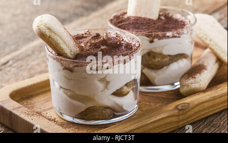Traditionelle italienische Dessert Tiramisu in Gläsern auf rustikalen Holztisch, Nahaufnahme, selektiver Fokus Stockfoto