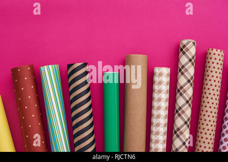 Geschenkverpackung. Rollen von bunten Geschenkpapier auf rosa Hintergrund. Stockfoto