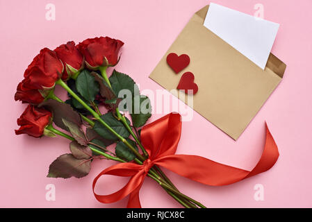 Die wahre Liebe. Umschlag mit Papier Hinweis, Blumenstrauß aus Rosen geschmückt mit Red Ribbon auf rosa Hintergrund Stockfoto