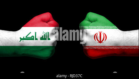 Flagge von Irak und Iran malte auf zwei geballte Fäuste nach einander auf schwarzem Hintergrund/Irak - Iran die Beziehungen Konzept Stockfoto