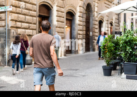 Orvieto, Italien outdoor Street in Umbrien historische Stadt Stadt Dorf gepflasterten Straße Gasse mit Menschen Touristen jungen Mann zu Fuß zurück in Summe Stockfoto