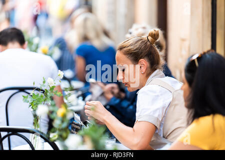 Rome, Italien - 4 September, 2018: Italienisches Restaurant Tische und Frau closeup Draußen sitzen im Cafe mit Bokeh der Menschen auf der Straße im historischen Zentrum der Stadt i Stockfoto