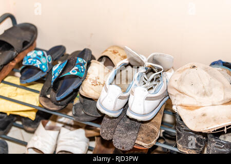 Viele Paare Schuhe auf Anzeige auf Regal Rack mit schmutzigen verschmutzt hat im rustikalen Cottage Farm House home Datscha closeup Stockfoto