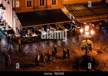 Lemberg, Ukraine - 31. Juli 2018: Antenne hohen Winkel Restaurant Basilico ukrainischen Stadt in der Altstadt Marktplatz mit nachts beleuchtete Menschen zu Fuß da Stockfoto