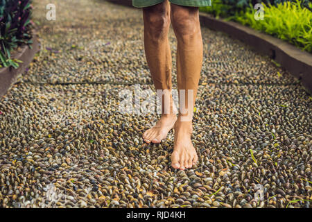 Menschen gehen auf eine strukturierte, mit Kopfstein Pflaster, Reflexzonenmassage. Pebble Stones auf dem Bürgersteig für Fußreflexzonenmassage. Stockfoto