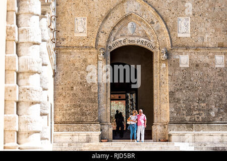 Siena, Italien - 27. August 2018: in der historischen, mittelalterlichen Altstadt Dorf in der Toskana für Monte dei Paschi Siena Eingang auf Gebäude und Touristen Zeichen pe Stockfoto