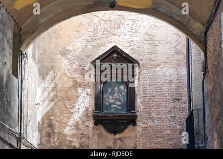 Siena, Italien - 27. August 2018: Dunkle schmale Gasse Straße arch im historischen mittelalterlichen Altstadt Dorf in der Toskana mit niemand und Malerei an der Wall von tun Stockfoto