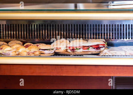 Anzeige von vielen großen Sandwiches hinter Glas Fenster der Speicher gefüllt mit Schinken, Käse und Tomaten in Italien mit Croissants und Brötchen Stockfoto