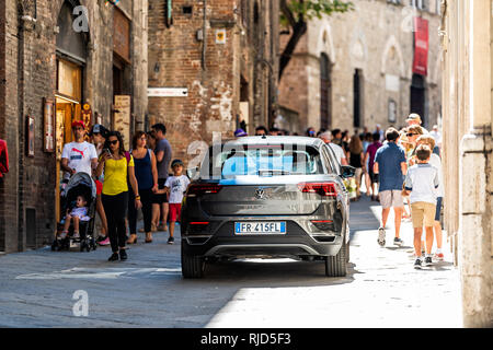 Siena, Italien - 27. August 2018: Straße in der historischen, mittelalterlichen Altstadt Dorf in der Toskana mit vielen Menschen Touristen zu Fuß oder mit dem Auto auf der schmalen Gasse Stockfoto