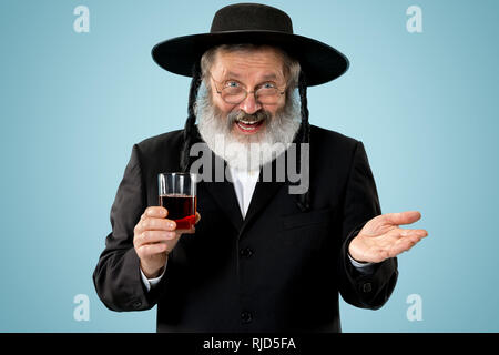 Portrait von alten Senior orthodoxen Hasdim jüdischen Mann mit koscherer Wein bei jüdischen Fest Purim im Studio. Die purim, jüdische, Festival, Urlaub, Feier, Judentum, Gebäck, Tradition, Cookie, Religion Konzept. Stockfoto