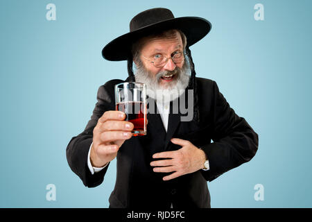 Portrait von alten Senior orthodoxen Hasdim jüdischen Mann mit koscherer Wein bei jüdischen Fest Purim im Studio. Die purim, jüdische, Festival, Urlaub, Feier, Judentum, Gebäck, Tradition, Cookie, Religion Konzept. Stockfoto