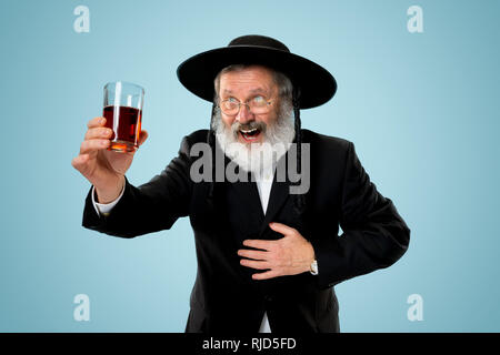 Portrait von alten Senior orthodoxen Hasdim jüdischen Mann mit koscherer Wein bei jüdischen Fest Purim im Studio. Die purim, jüdische, Festival, Urlaub, Feier, Judentum, Gebäck, Tradition, Cookie, Religion Konzept. Stockfoto