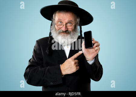 Portrait von alten Senior orthodoxen Hasdim jüdischen Mann mit Handy bei jüdischen Fest Purim im Studio. Die purim, jüdische, Festival, Urlaub, Feier, Judentum, Tradition, Business, Kommunikation, Religion Konzept. Stockfoto