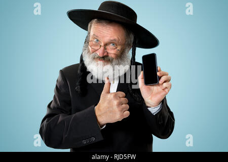 Portrait von alten Senior orthodoxen Hasdim jüdischen Mann mit Handy bei jüdischen Fest Purim im Studio. Die purim, jüdische, Festival, Urlaub, Feier, Judentum, Tradition, Business, Kommunikation, Religion Konzept. Stockfoto