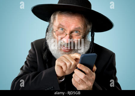 Portrait von alten Senior orthodoxen Hasdim jüdischen Mann mit Handy bei jüdischen Fest Purim im Studio. Die purim, jüdische, Festival, Urlaub, Feier, Judentum, Tradition, Business, Kommunikation, Religion Konzept. Stockfoto