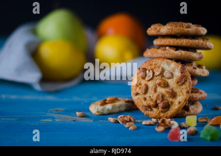 Runde orange Biscuits mit bunten kandierte Früchte und ein Stück saftige Orange liegen auf einem Holztisch Stockfoto