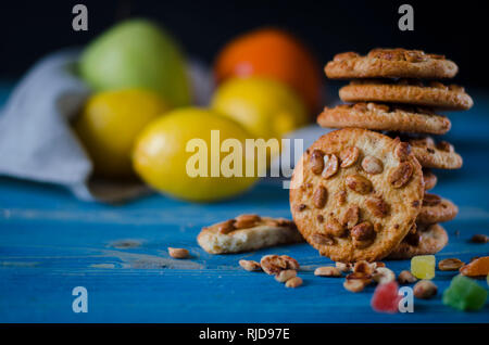 Runde orange Biscuits mit bunten kandierte Früchte und ein Stück saftige Orange liegen auf einem Holztisch Stockfoto