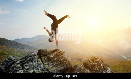 Erstaunlich yoga Mann sie einen Handstand auf Rock. Mixed Media Stockfoto