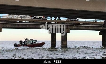 Die Küstenwache ist auf der Suche nach einem möglichen Person im Wasser nach Berichten eines Fahrzeugs über den Causeway Brücke gehen im Mile Marker 12 in Lake Pontchartrain, Louisiana, 24. Januar 2018. Coast Guard Sektor New Orleans watchstanders erhielt einen Bericht von Causeway Bridge Behörden bezüglich einer möglichen Fahrzeug im Wasser nach dem Abgeordneten die fehlenden Leitplanke von der Brücke, sowie Propan Tanks in der Fahrbahn berichtet. Stockfoto