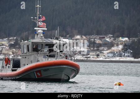 Mitglieder der Coast Guard Station Juneau an Bord eines 45-Fuß-antwort Boot - Medium, den Weg hin zu einem Dummy schwimmend im Wasser beim Leiten der Mann über Bord Ausbildung in Juneau, Alaska, Jan. 24, 2018. Station Juneau durchgeführt, um die Mann-über-Bord-Position Bohrer bei Frost zu erhalten neue Mitglieder boatcrew qualifiziert. Stockfoto