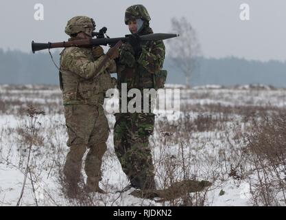 Ein rumänischer Soldat (rechts), um die rumänische Armee Boden Base Air Defence Loslösung, schwarzen Fledermäusen zugeordnet, lädt eine Granate in die Rakete angetrieben Granatwerfer für Sgt. Stephen Lennon (links), ein Soldat an die Zentrale und Hauptverwaltung Truppe, 3 Staffel, 2. Kavallerie Regiments, zugeordnet in einem Bereich in der Nähe der Bemowo Piskie, Polen, Jan. 24, 2018. Die einzigartige, multinationalen Battle Group, bestehend aus USA, Großbritannien, Kroatischen und Rumänische Soldaten dienen, die mit der polnischen 15 mechanisierte Brigade als Abschreckung Kraft im Nordosten Polens in der Unterstützung der NATO-Präsenz verstärkt nach vorne. Stockfoto