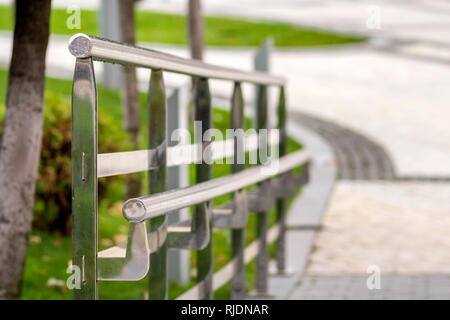 Metallzaun Konstruktion aus glänzenden nassen Edelstahl Rohre entlang der Straße Highway auf der Kopie Raum Hintergrund von grünem Gras Landschaft und Weiße verschwommene Stockfoto