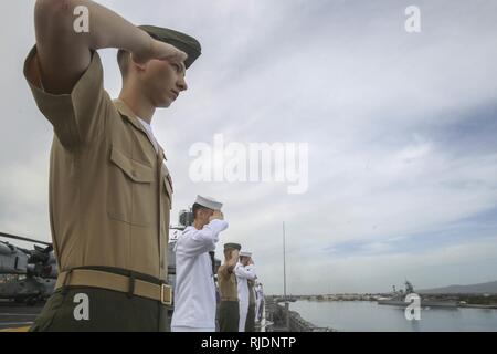 PEARL HARBOR NAVAL BASE, HI-Marinesoldaten und Matrosen mit dem 15 Marine Expeditionary Unit und Amerika amphibischen Bereit Gruppen an Bord amphibisches Schiff USS America (LHA 6) Salute, wie sie das USS Arizona Memorial verlassen, Jan. 25, 2018. Manning der Schienen ist ein Naval Tradition jede Bereitstellung von Schiff führt und ist eine Methode der ehrenkompanie oder Rendering Ehren durch Marineschiffe verwendet. 15 Marine Expeditionary Unit und Amerikanischen amphibische Gruppe bereit sind, die in den USA 7 Flotte Verantwortungsbereich regionale Partnerschaften zu verbessern und dienen als ready-Funktion für eine Stockfoto