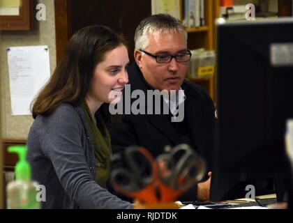 Emily Copeland, neue Bibliothekarin 325 Force Support Squadron, und Mark Rix, 325 Force Support Squadron Kraft Entwicklung Flug Chief, Prozessdaten auf Copeland's Computer an der Tyndall Air Force Base, Fla., Jan. 18, 2018. Wie die neue Bibliothekarin, Copeland wird viele Hüte: Facility Manager, Resource Manager, Information Technology Equipment, Depotbank und Tätigkeiten Direktor tragen. Das Tyndall Bibliothek unterstützt die Gemeinschaft durch Bildung, Referenz- und Lesematerial für Flieger und Familie Mitglieder aller Altersgruppen. Stockfoto