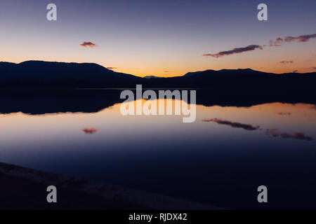 Malerische Ansicht von wunderbaren Sonnenuntergang Himmel über Bergrücken und ruhigen Wasser Stockfoto