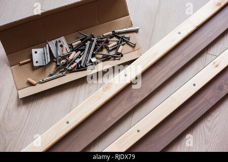 Möbelbeschläge, Schrauben und andere Teile in offenen craft Box auf dem Boden liegend, Möbel Montage zu Hause. Stockfoto