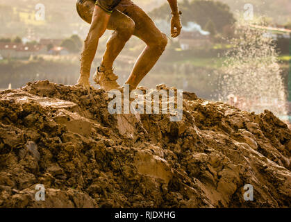 Trail Running Athleten Überschreiten der schmutzigen Pfütze in einem Mud Racer. Stockfoto