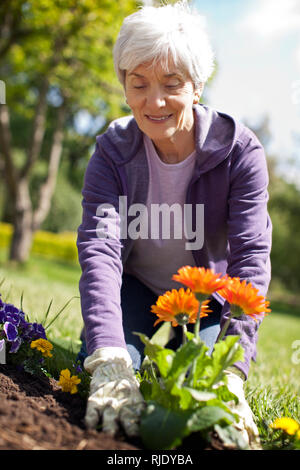 Gerne ältere Frau Spaß im Garten in ihrem Hinterhof. Stockfoto