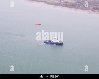 Der Küstenwache Sektor/Air Station Corpus Christi MH-65 Dolphin Helikopter der Besatzung und des Schiffes Signet Polaris führen ihre erste Ausbildung evolution 18.01.2018, in Corpus Christi Bay. Die Ausbildung simuliert das Heben eines verletzten oder kranken Person vom Deck eines fahrenden Schiffes, auf einem Hubschrauber für den Transport auf ein höheres Niveau der medizinischen Versorgung. Stockfoto