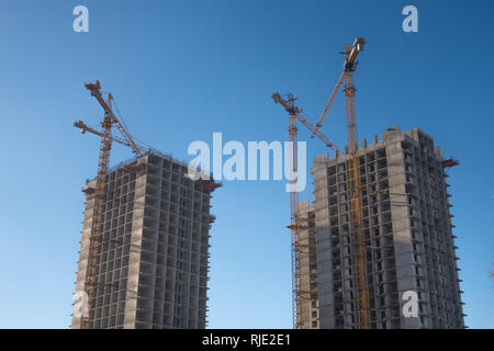 Bau eines Hochhauses mit einem Kran. Bau von Hochhaus auf dem Hintergrund des blauen Himmels Stockfoto