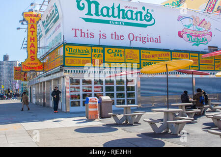 24. März 2018: Ikonischer Boardwalk mit Parachute Drop und Nathans Hot Dogs in Coney Island, Brooklyn Stockfoto