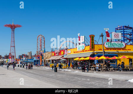 24. März 2018: Ikonischer Boardwalk mit Parachute Drop und Nathans Hot Dogs in Coney Island, Brooklyn Stockfoto