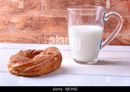 Schokolade und Puderzucker Softeis Ringe und Glas mit Milch auf Holztisch. traditionelles Frühstück. Stockfoto