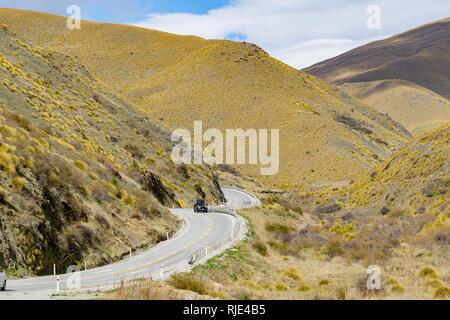 Kurvenreiche Straße durch South Island tussock bedeckte Berge Stockfoto