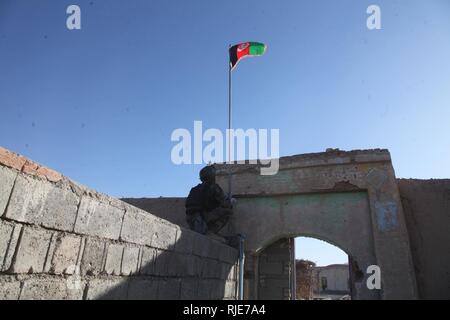 Kommandos aus dem 9 Special Operations Kandak beseitigt 36 Taliban-Kämpfer Angreifen der Anar Dara Bezirk Mitte, Farah Province, Afghanistan, Jan. 12, 2018. Innerhalb einer Woche nach Kabul Friedenskonferenz, die Taliban mehrere Angriffe in Farah gestartet. Die Taliban Angriffe in ihrem erklärten Ziel, Gedrückthalten der Taste Bezirkszentren zu scheitern. Ein afghanischer Commando wirft der nationalen Flagge über ein Mittel, das in der Provinz Farah. Stockfoto