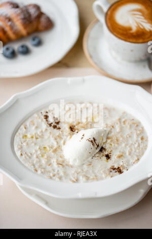 Schale frühstück Haferflocken mit weichem italienischem Käse und Zimt. Croissants, Kaffee und andere Gerichte auf den Tisch im Restaurant Stockfoto