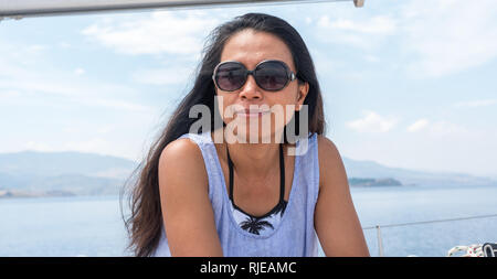 Frau mit Sonnenbrille auf Segelboot auf der Suche nach Fotograf Stockfoto